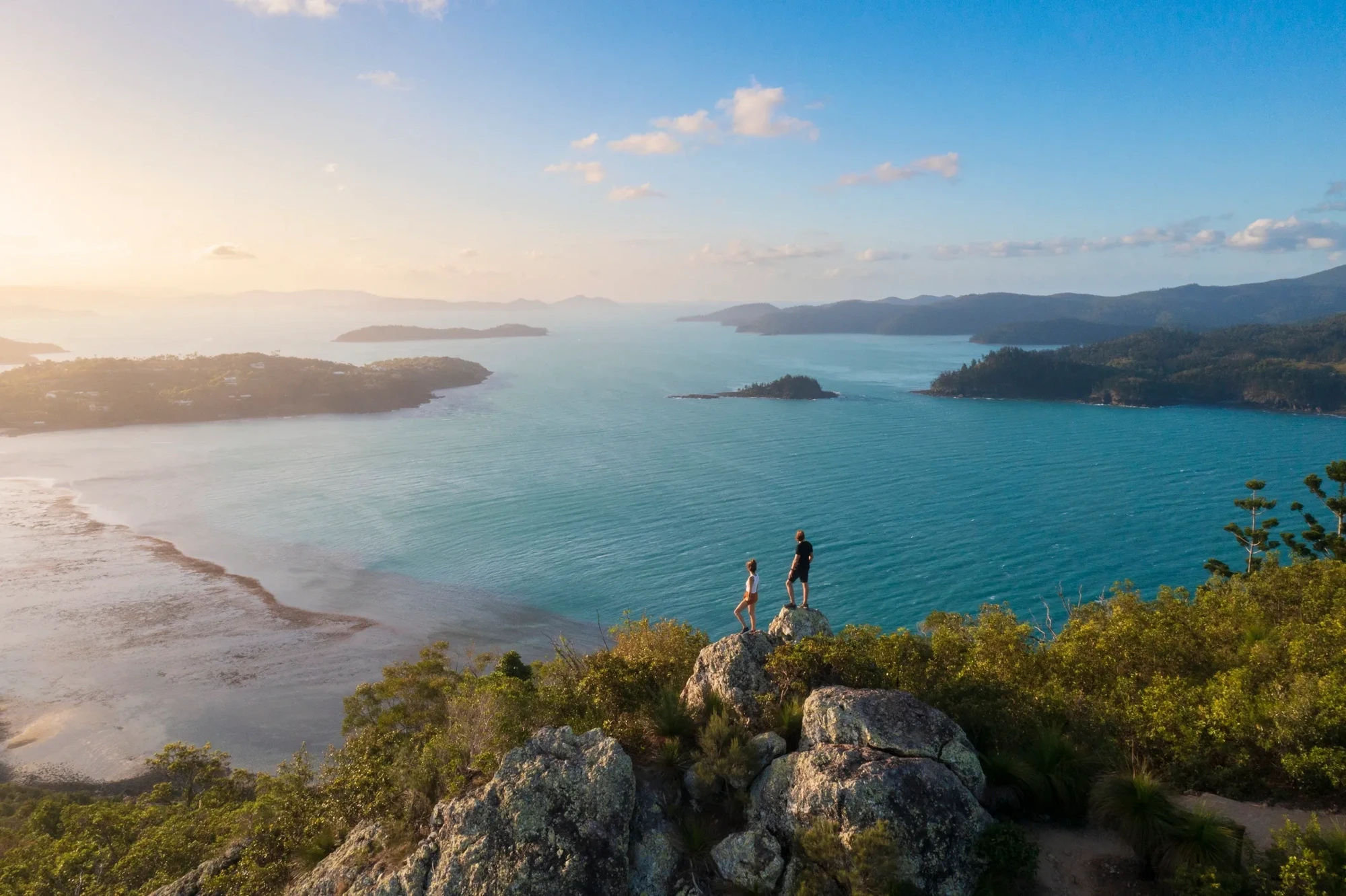 A couple standing on a cliff overlooking the Whitsundays