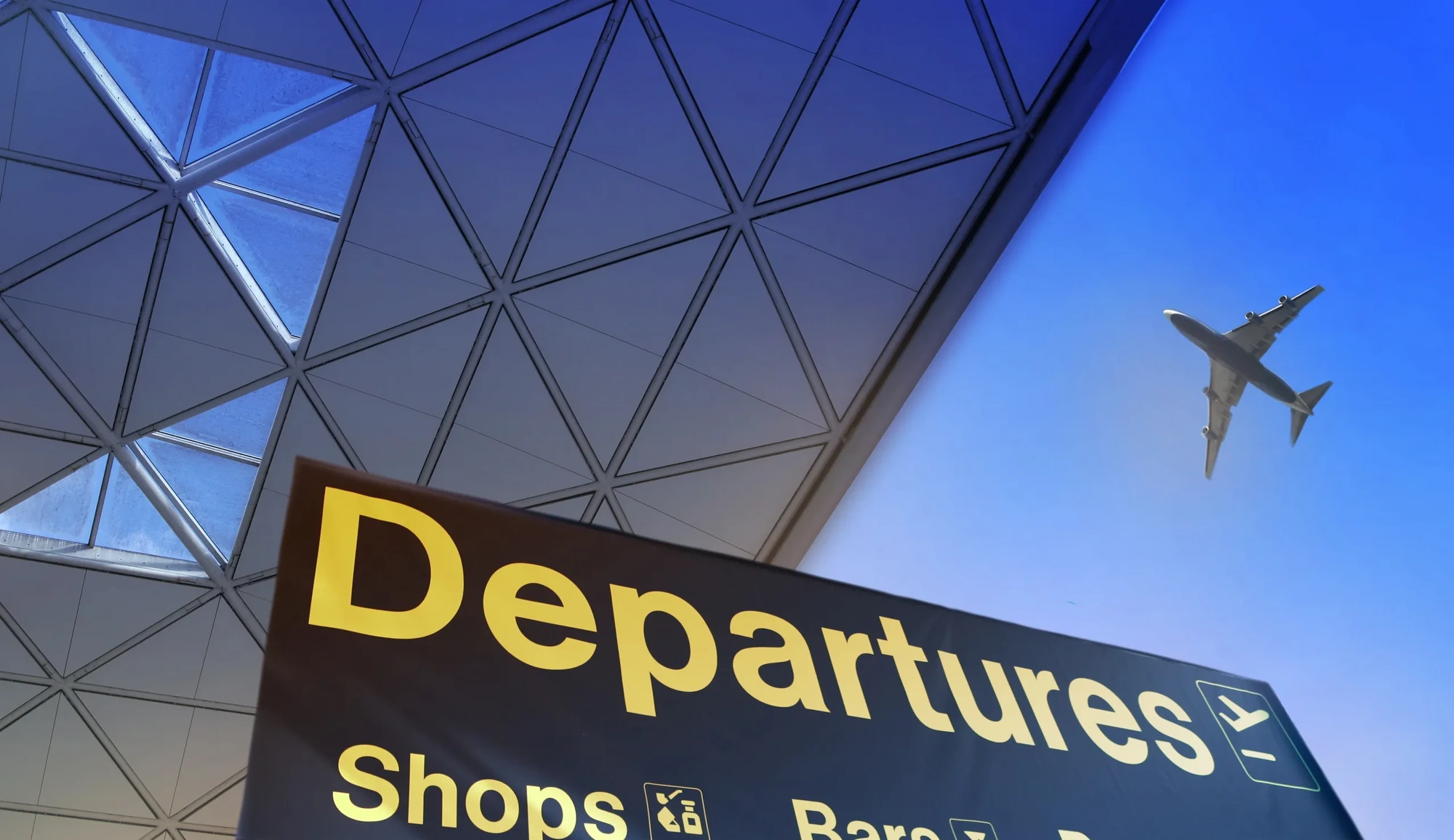 Airport departures sign with aircraft above