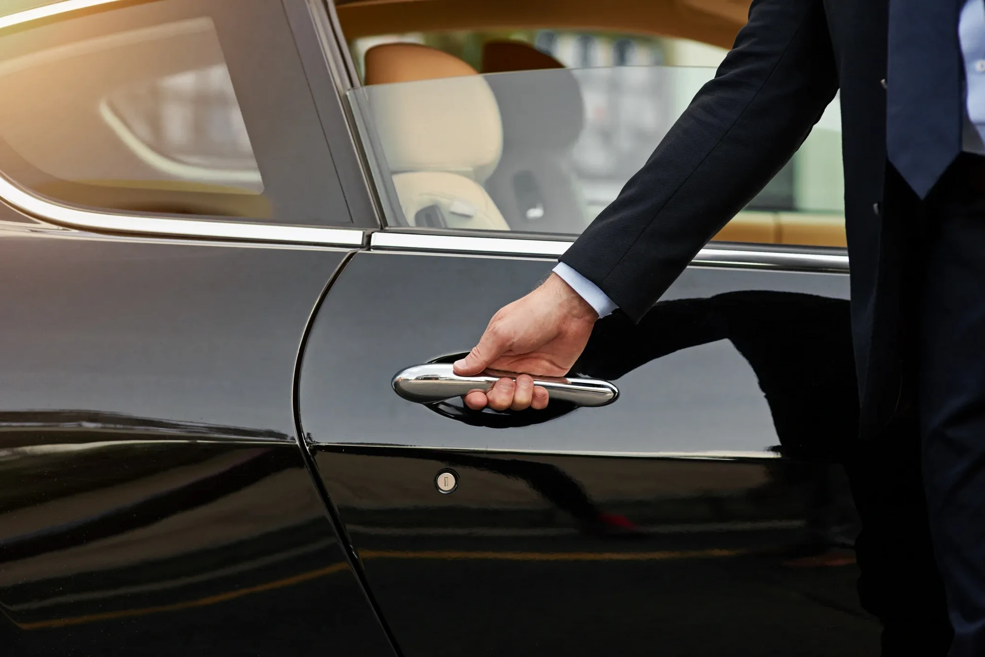 Chauffeur waiting beside an executive SUV at sunset